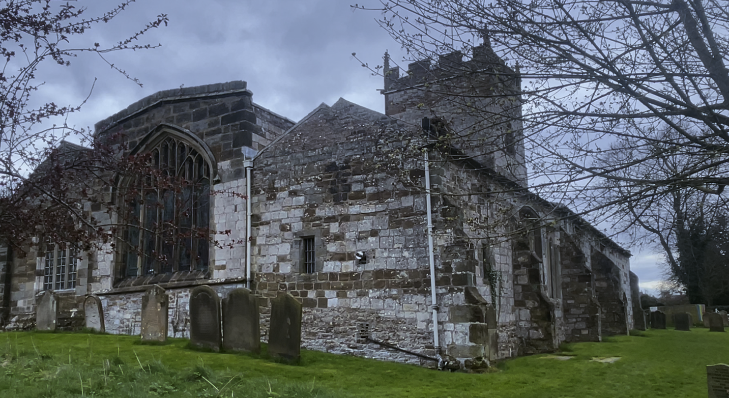 A stone building with a cemetery
Description automatically generated